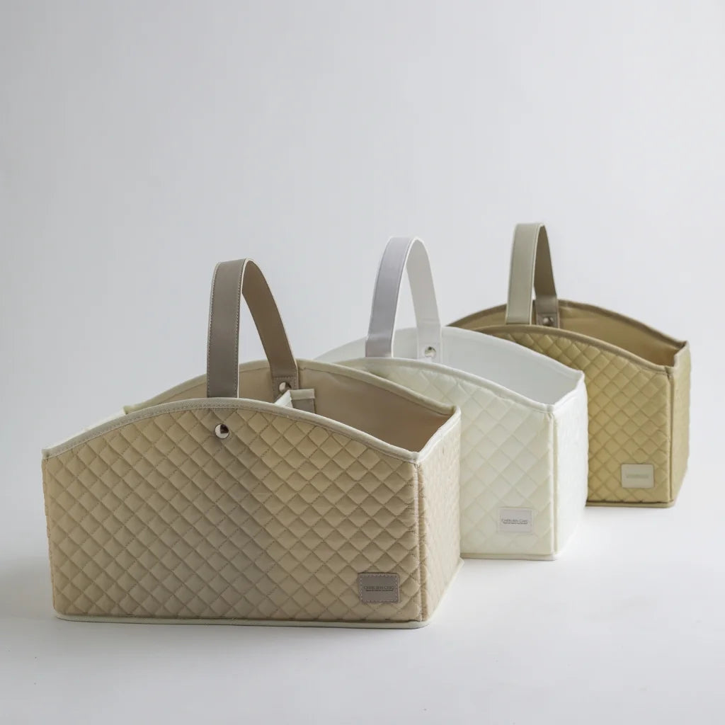 A trio of quilted baby storage caddies in different neutral tones—beige, white, and taupe—displayed elegantly for a sophisticated nursery organization solution.