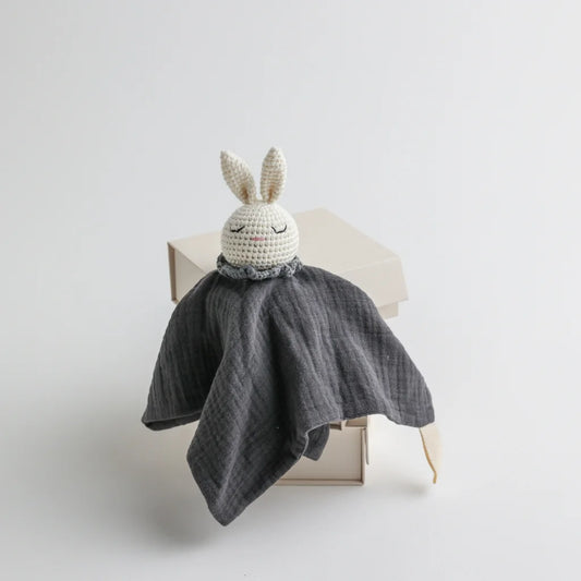 A charcoal grey muslin baby comforter with a crocheted bunny head, offering a modern and stylish look.