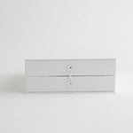 A classic white keepsake storage box with a secure string closure, offering a sophisticated and organized way to store baby’s milestones.