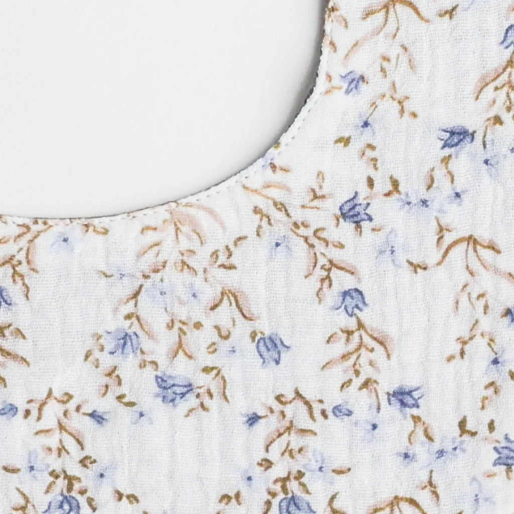 A detailed close up of high-quality organic cotton fabric of a floral-patterned baby bib, highlighting its fine texture and delicate design.