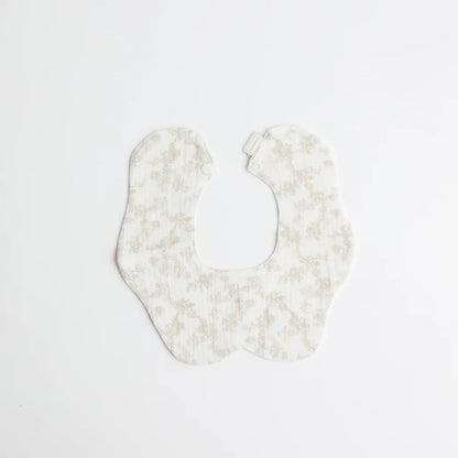 A soft white baby bib decorated with a subtle beige floral print, crafted for gentle wear on a baby’s delicate skin.