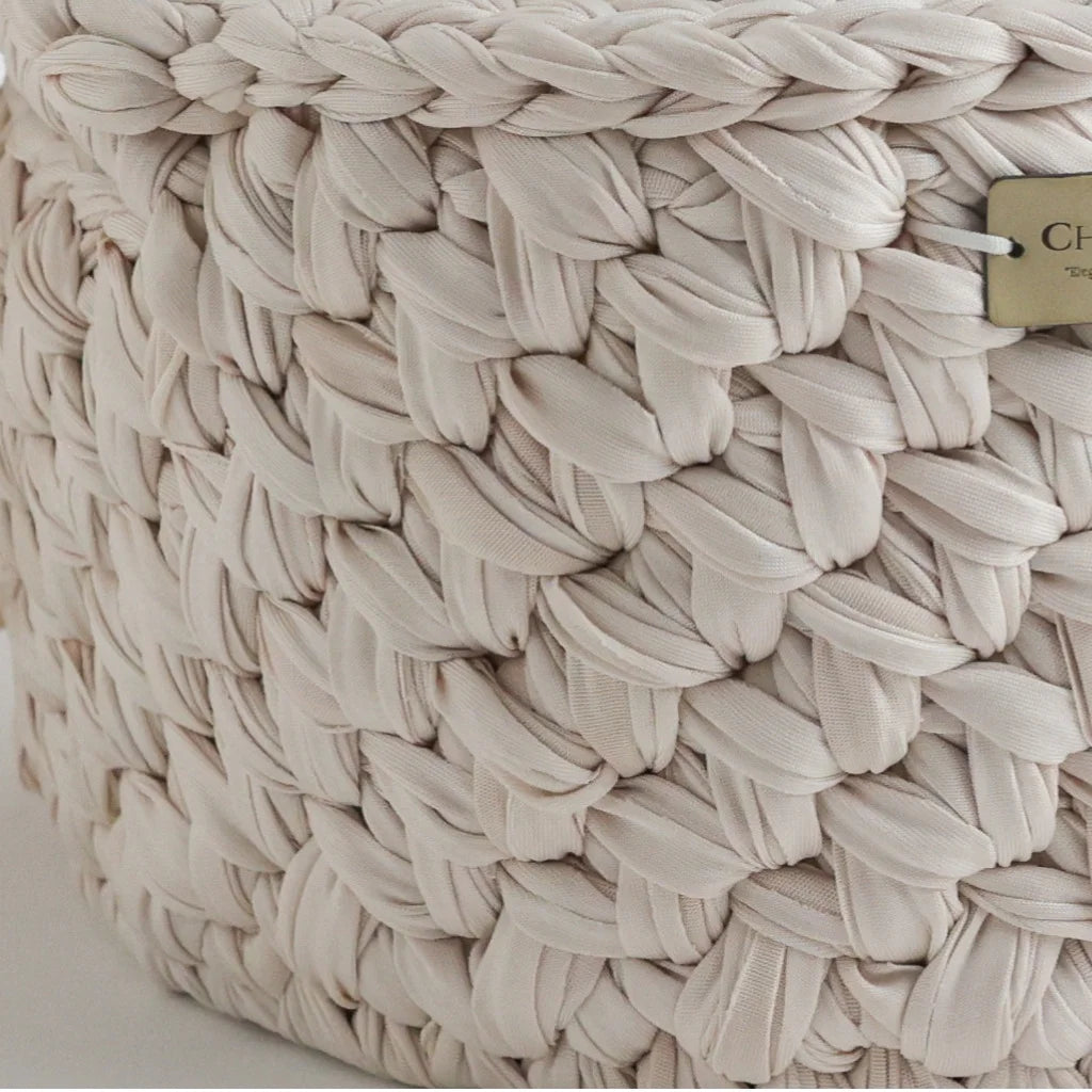A detailed close-up of the woven knit texture of a Cherubin Chic storage basket in beige, highlighting the intricate braiding and craftsmanship.