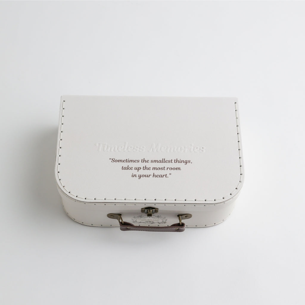 A timeless white keepsake suitcase with embossed "Timeless Memories" text and an inspiring quote on the lid: "Sometimes the smallest things take up the most room in your heart.