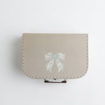 A beige keepsake suitcase with a subtle embossed bow illustration and "Timeless Memories" text for elegant baby keepsakes.