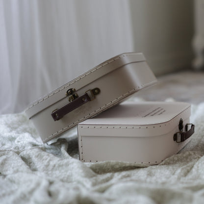 Two vintage memory suitcases placed in a cozy setting with soft lighting, highlighting their elegant craftsmanship and brown leather handles.