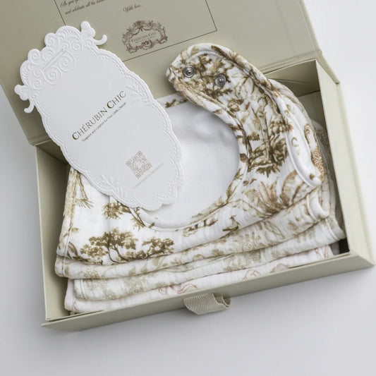 A close-up of a set of luxury muslin baby bibs, neatly packaged in a premium gift box with an elegant Cherubin Chic branding tag.