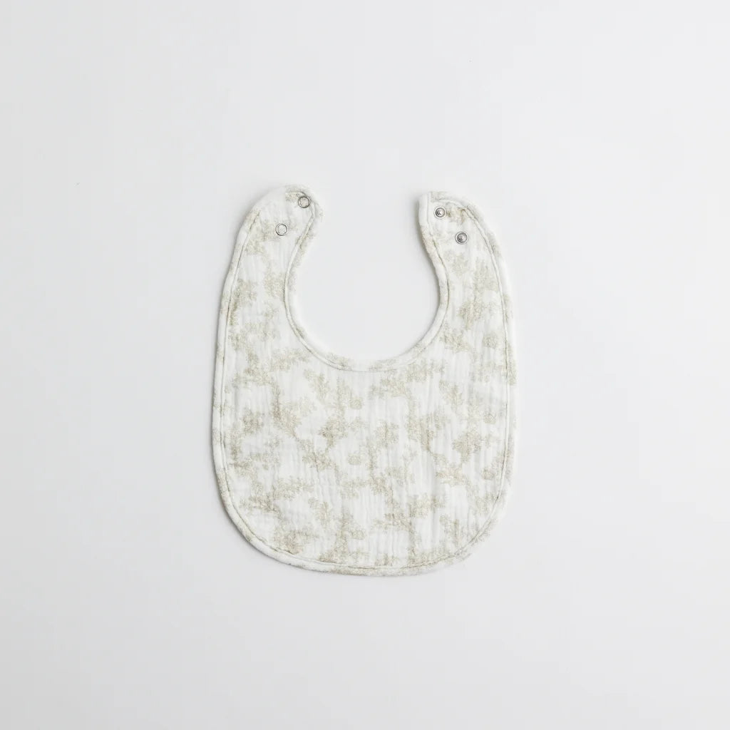 A classic baby bib with an elegant floral print in muted tones. The soft muslin fabric provides gentle protection for a baby's delicate skin.