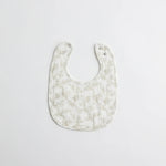 A classic baby bib with an elegant floral print in muted tones. The soft muslin fabric provides gentle protection for a baby's delicate skin.