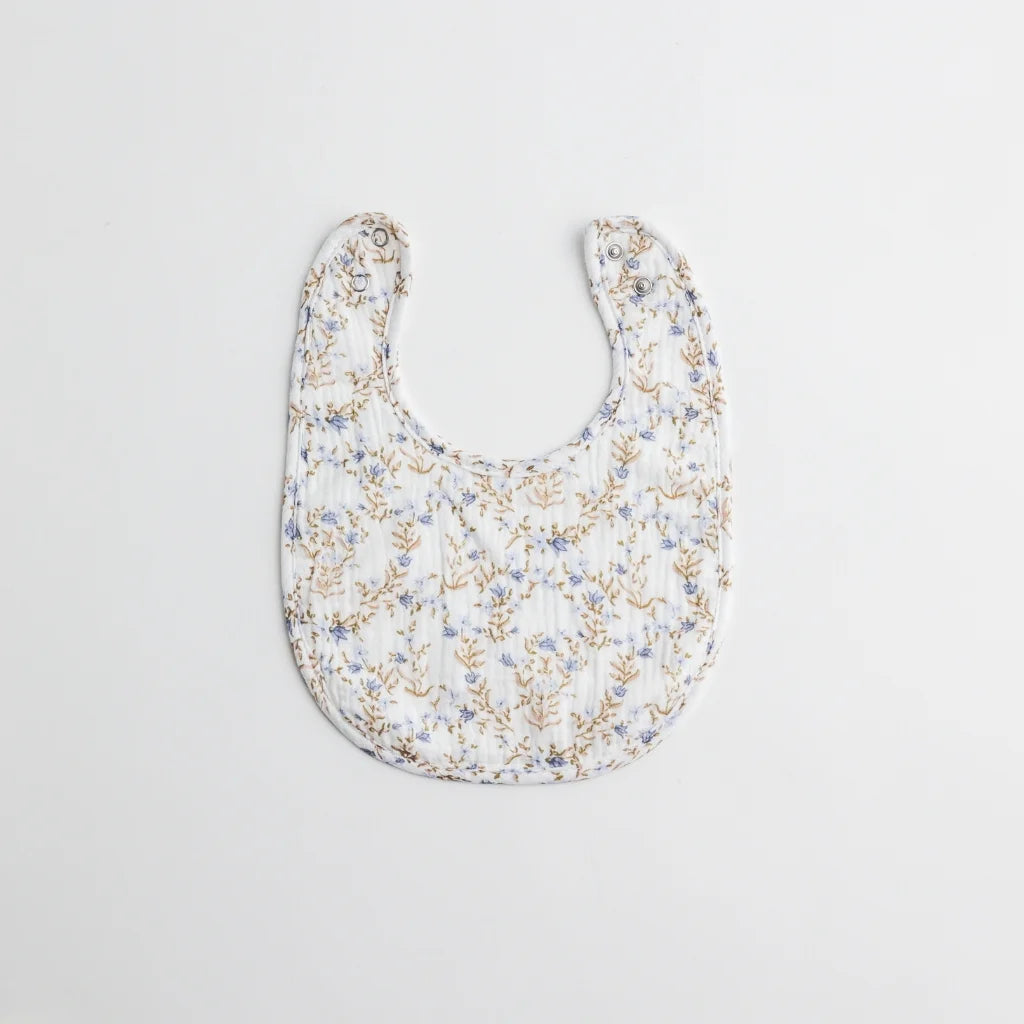 A baby bib with a delicate blue floral print on a white muslin fabric. The lightweight and breathable material is perfect for everyday wear.