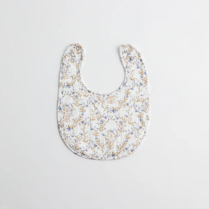 A baby bib with a delicate blue floral print on a white muslin fabric. The lightweight and breathable material is perfect for everyday wear.