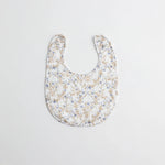 A baby bib with a delicate blue floral print on a white muslin fabric. The lightweight and breathable material is perfect for everyday wear.