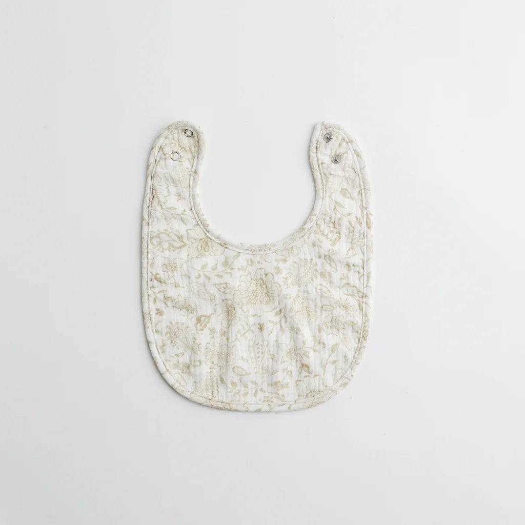 A beautifully patterned baby bib with intricate golden floral motifs. The soft, breathable fabric ensures a comfortable fit for little ones.
