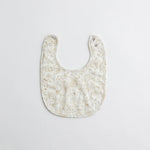 A beautifully patterned baby bib with intricate golden floral motifs. The soft, breathable fabric ensures a comfortable fit for little ones.