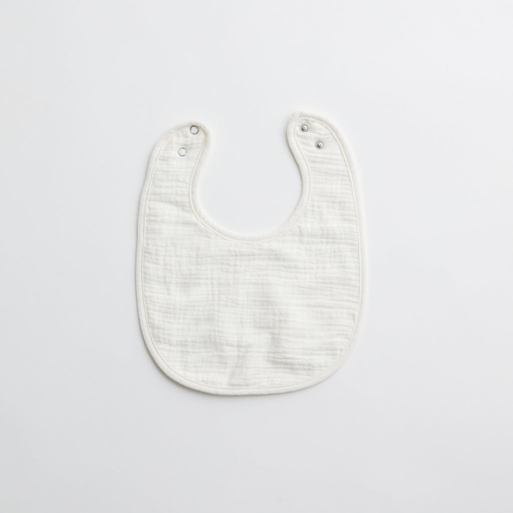 A crisp white muslin baby bib, highlighting its soft and gentle fabric.