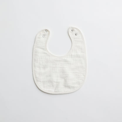 A crisp white muslin baby bib, highlighting its soft and gentle fabric.