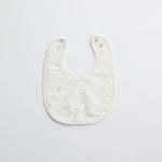 A crisp white muslin baby bib, highlighting its soft and gentle fabric.