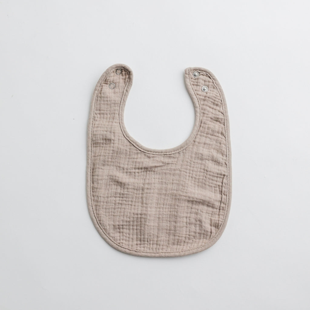 A taupe muslin baby bib with a subtle earthy tone, adding a sophisticated touch to baby essentials.