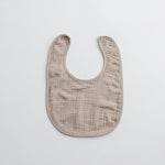 A taupe muslin baby bib with a subtle earthy tone, adding a sophisticated touch to baby essentials.