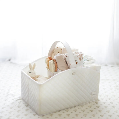 A white quilted baby storage caddy filled with baby essentials, set against a softly lit nursery background for a cozy aesthetic.