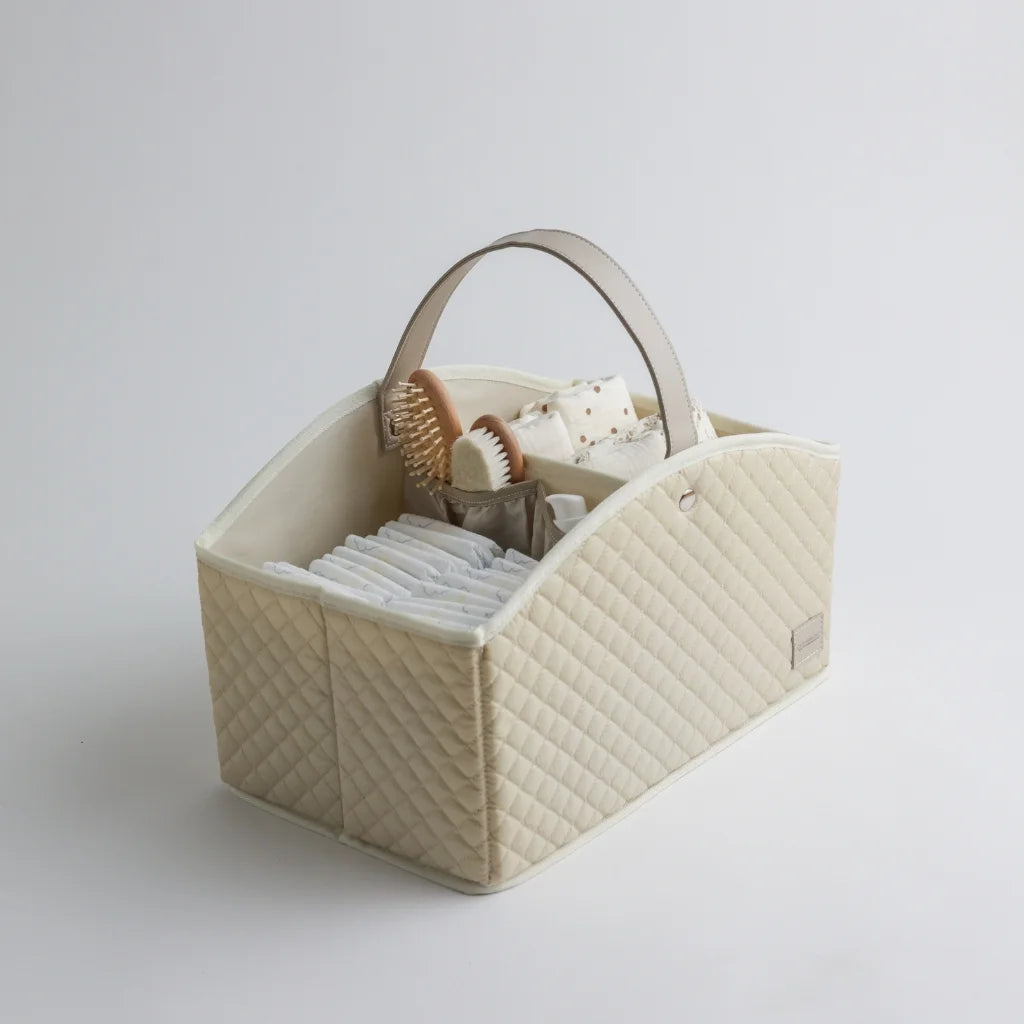 Side view of a beige quilted baby storage caddy with a sturdy handle, showcasing compartments neatly organized with baby essentials.