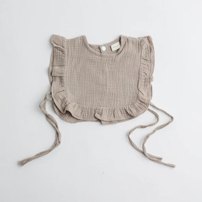 A taupe-colored muslin ruffle bib with frilly edges, showcasing a neutral and timeless design.