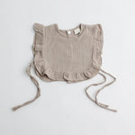 A taupe-colored muslin ruffle bib with frilly edges, showcasing a neutral and timeless design.
