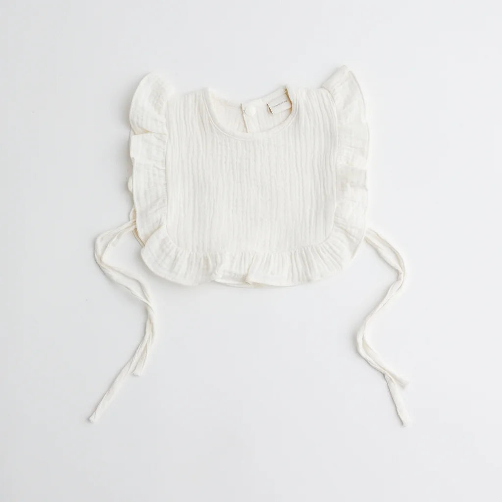 A classic white organic muslin ruffle bib, showcasing its airy texture and elegant design.