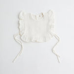 A classic white organic muslin ruffle bib, showcasing its airy texture and elegant design.