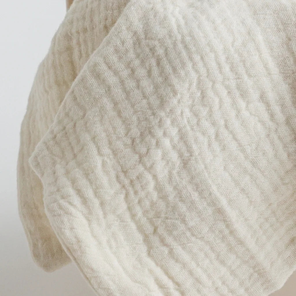 Close-up of the off-white muslin fabric, showcasing its delicate texture and breathable material.