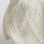Close-up of the off-white muslin fabric, showcasing its delicate texture and breathable material.