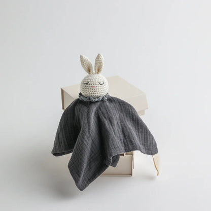 A charcoal grey muslin baby comforter with a crocheted bunny head, offering a modern and stylish look.