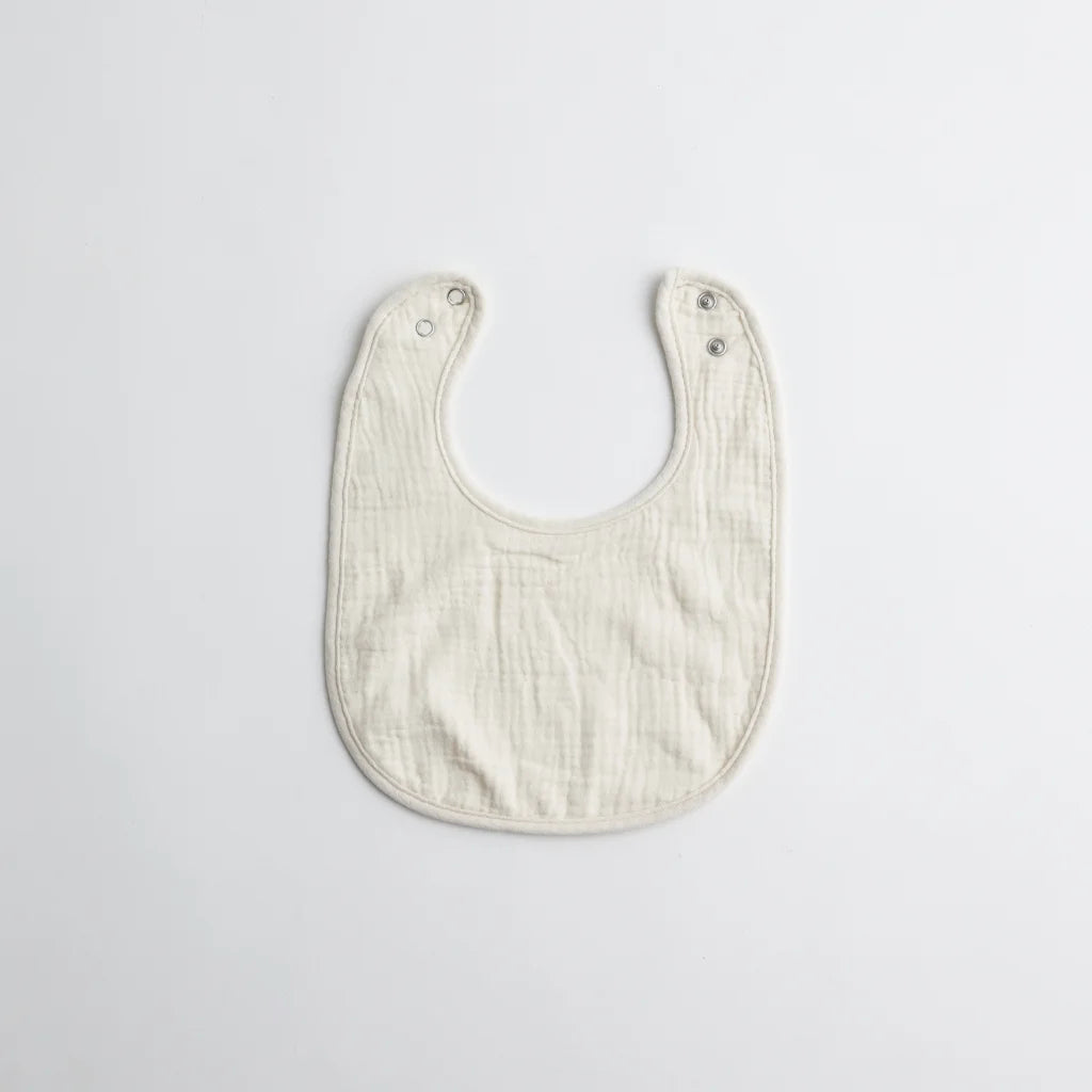 A simple white muslin baby bib, crafted from soft organic cotton, featuring snap buttons for convenience.