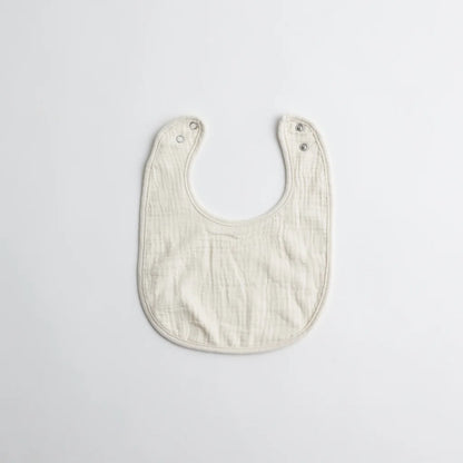 A simple white muslin baby bib, crafted from soft organic cotton, featuring snap buttons for convenience.